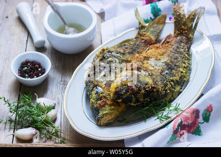 Traditionelle Moldauischen oder rumänischen Gericht, gebratener Fisch im Mais vor dem Panieren mit Knoblauch Sauce serviert. Rustikaler Stil, selektiven Fokus. Stockfoto