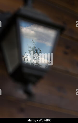 Bewölkter Himmel und Baum Silhouette reflektiert in vintage Laterne Stockfoto