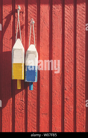 Angeln Bojen, verwendet, um zu kennzeichnen, wo der Hummer Töpfe gesunken sind, hängen an einem roten Holzwand in Prince Edward Island, Kanada. Spcae für Ihren Text. Stockfoto