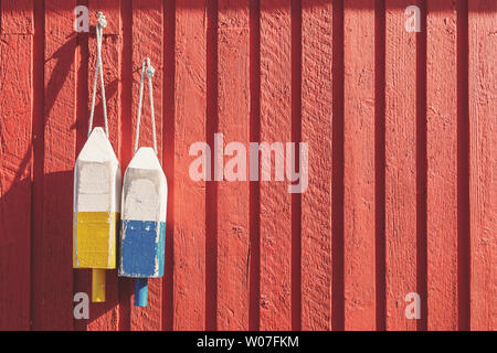 Angeln Bojen, verwendet, um zu kennzeichnen, wo der Hummer Töpfe gesunken sind, hängen an einem roten Holzwand in Prince Edward Island, Kanada. Spcae für Ihren Text. Stockfoto