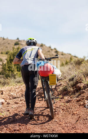 Man Radfahrer seine touring Bike über die Hügel entlang der G10 Long distance Trail in der Montes Universales Bergen des östlichen Spanien drücken Stockfoto