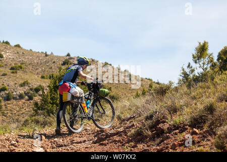 Man Radfahrer seine touring Bike über die Hügel entlang der G10 Long distance Trail in der Montes Universales Bergen des östlichen Spanien drücken Stockfoto