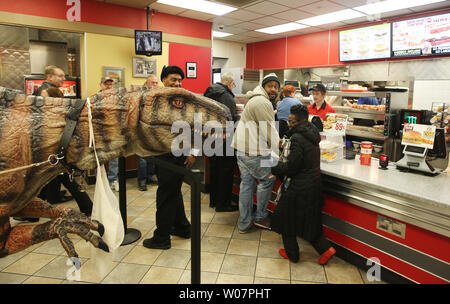 Kunden, die in der Schlange bei einem Hardee fast food Restaurant warten, von einem Mann in einem Dinosaurier Kostüm gekleidet, wie er geht durch während einer Fundraising frühstück Stunde in St. Louis am 12 Februar, 2016 aufgeschreckt. Foto von Bill Greenblatt/UPI Stockfoto