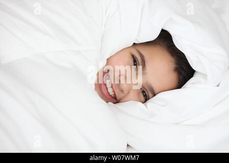 Porträt eines indischen Mädchen auf dem Bett liegend und lächelnd Stockfoto