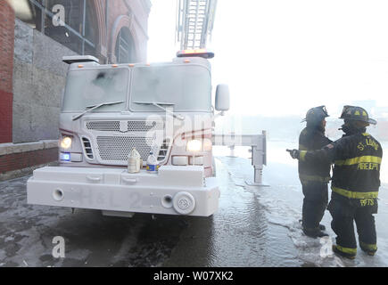 St. Louis Feuerwehrleute versuchen, zu entscheiden, wie Sie de-ice Vorne mit Haken und Leiter 2, während Wasser auf ein 6-stöckiges, hohes Lagerhaus in acht Grad in St. Louis am 18. Dezember 2016 gesprüht wird. Zwei Obdachlose waren gerettet aus dem leerstehenden Gebäude, das während der Nacht verbrannt. Foto von Bill Greenblatt/UPI Stockfoto