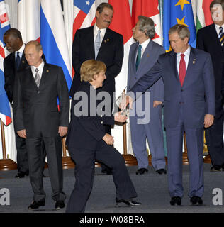 Der russische Präsident Wladimir Putin (L) blickt zurück wie der US-Präsident George W. Bush (R) hilft die Deutsche Bundeskanzlerin Angela Merkel auf der Bühne für eine Staats- und Regierungschefs der G8-Gruppe Foto zu kommen, der auf die letzte Sitzung des G8-Gipfels in Sankt Petersburg, Russland am 17. Juli 2006 Von links in der oberen Reihe sind der südafrikanische Präsident Thabo Mbeki, der mexikanische Präsident Vicente Fox, der japanische Ministerpräsident Junichiro Koizumi und der kanadische Premierminister Stephen Harper. (UPI Foto/Dima Volgin) Stockfoto