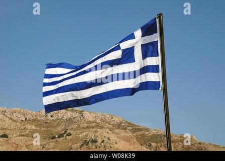 Die griechische Flagge fliegen an der Küste von Livadia auf der griechischen Insel Tilos. Stockfoto