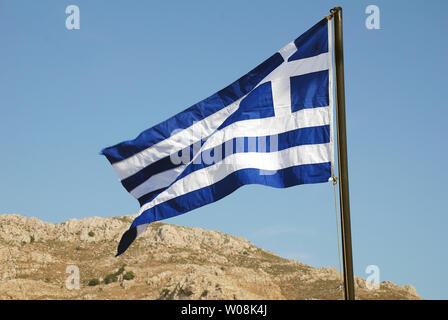 Die griechische Flagge fliegen an der Küste von Livadia auf der griechischen Insel Tilos. Stockfoto