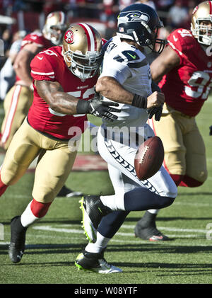 Seattle Seahawks QB Russell Wilson (R) ungeschickte Versuche, wie er von San Francisco 49ers NaVorro Bogenschützen im ersten Quartal bei Candlestick Park in San Francisco am 8. Dezember 2013 entlassen wird. Die 49ers besiegten die Seahawks 19-17. UPI/Terry Schmitt Stockfoto