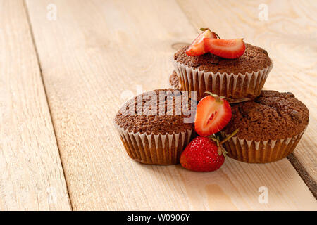 Pyramide von Muffins mit frischen Erdbeeren auf hellem Holztisch. Stockfoto