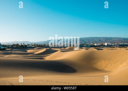 Panoramablick auf die Landschaft von Maspalomas Sand Dünen der Wüste mit der Stadt und Berge im Hintergrund an einem sonnigen Sommertag Stockfoto