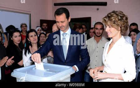 In diesem Foto von Syriens nationale Nachrichtenagentur veröffentlicht, der syrische Präsident Baschar al-Assad und der syrischen First Lady Asma Assad Stimmen bei der Präsidentschaftswahl des Landes in einem Wahllokal in Maliki, einer Wohngegend im Zentrum der Hauptstadt Damaskus, Syrien, am 3. Juni 2014, Syrer aufgereiht vor wahllokalen in den von der Regierung kontrollierten Gebieten um das Land zu Stimme Dienstag in der Präsidentenwahl wird allgemein erwartet, dass Assad zu gewinnen, aber die Opposition im Exil hat die Zugeschlagen als "Farce". UPI Stockfoto