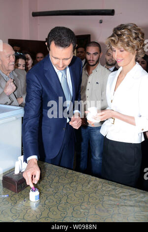 In diesem Foto von Syriens nationale Nachrichtenagentur veröffentlicht, der syrische Präsident Baschar al-Assad und der syrischen First Lady Asma Assad Stimmen bei der Präsidentschaftswahl des Landes in einem Wahllokal in Maliki, einer Wohngegend im Zentrum der Hauptstadt Damaskus, Syrien, am 3. Juni 2014, Syrer aufgereiht vor wahllokalen in den von der Regierung kontrollierten Gebieten um das Land zu Stimme Dienstag in der Präsidentenwahl wird allgemein erwartet, dass Assad zu gewinnen, aber die Opposition im Exil hat die Zugeschlagen als "Farce". UPI Stockfoto