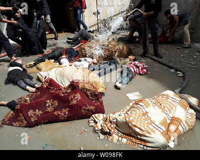 *** Herausgeberanmerkung INHALT *** syrischer Männer streuen sie Wasser auf die Leichen der Zivilisten, nachdem ein angeblicher chemischer Angriff auf die Rebellen gehaltene Stadt Douma in Syrien. Mindestens 78 Zivilisten, darunter Frauen und Kinder, starben nach ersten Ergebnissen. Foto von Mohammed Hassan/UPI Stockfoto