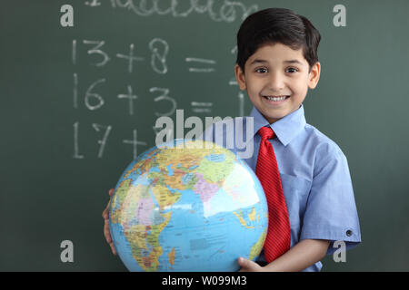 Porträt von Schuljunge hält einen Globus und lächelnd Stockfoto