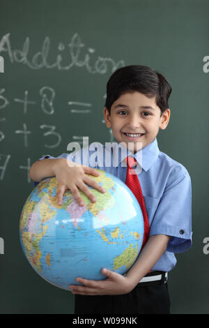 Porträt von Schuljunge hält einen Globus und lächelnd Stockfoto