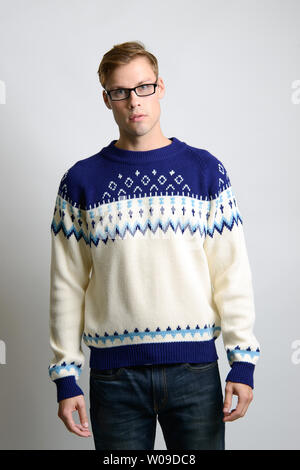 Ein braunes kaukasisches männliches Model posiert im Vintage-Pullover und trägt eine Brille, ein Vintage-Mode-Editorial für Männer. Stockfoto