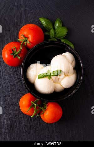 Lebensmittelzutat Konzept organische Mozzarella in schwarz Keramiktasse mit Tomaten und Basilikum mit Kopie Raum Stockfoto