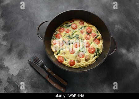 Frittata aus Eier, Pilze, Tomaten und Spinat in einer Pfanne serviert. Italienische Küche Stockfoto