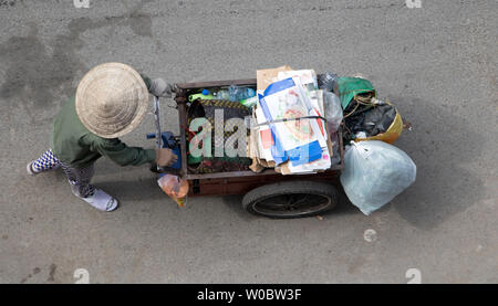 Vietnamesische Frau treibt einen Wagen voller Sammlung von verwertbaren Abfällen in den Straßen von Ho Chi Minh Stadt. Stockfoto