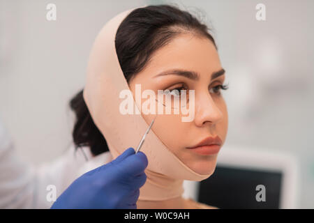 Dark-eyed Frau Gefühl sorgen vor dem Gesicht Chirurgie Stockfoto