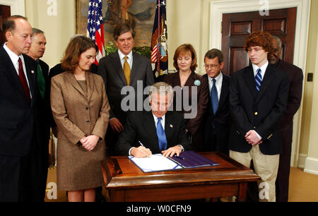 Präsident George W. Bush unterzeichnet den Garrett Lee Smith Memorial Handeln am 21. Oktober 2004 im Weißen Haus in Washington. Das Gesetz stellt Unterstützung für psychische und Verhaltensstörungen Gesundheit an amerikanischen Universitäten. Familienangehörige von Garrett Smith und Kongressabgeordnete Blick auf. (UPI Foto/Michael Kleinfeld) Stockfoto