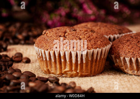 Muffins mit Kaffeebohnen auf eine Jutetasche mit dunklem Hintergrund. Detailansicht. Stockfoto