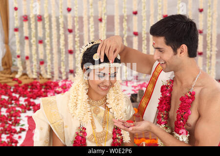 Durchführung Sindoor Daan Zeremonie in Malayalee Hochzeit paar Stockfoto