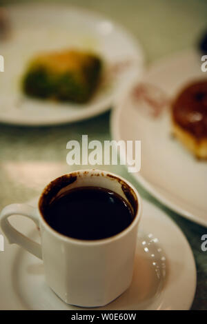 Einen kleinen türkischen Kaffee, aus fein gemahlenen Bohnen und heißes Wasser, mit einem Stück baklava und andere Süßigkeiten in den Hintergrund in Istanbul, Türkei Stockfoto