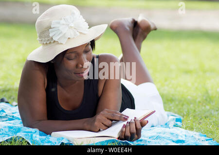 Diese junge Frau liegen im Schatten eines Baumes ist ruhig lesen. Stockfoto