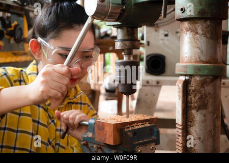 Frauen, Handwerk ist der Bohrer Holz an einer Werkbank mit Bohrmaschine Elektrowerkzeuge bei Tischler Maschine in der Werkstatt Stockfoto