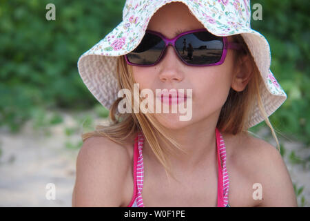 Porträt von einem achtjährigen Mädchen mit Sonnenbrille und Hut Stockfoto
