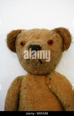 Seitlicher Blick auf eine alte gefüllte und genähten Teddybär an eine Wand gelehnt Stockfoto