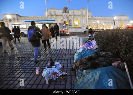 Pendler, die zu Fuß von der Union Station entfernt, als heimatloser Mann schläft am 27. Januar 2010. Eine viertel Meile entfernt, Präsident Barack Obama für die Wirtschaft und Arbeitsplätze konzentrieren wird, wenn er die Lage der Union zu einer gemeinsamen Sitzung des Kongresses liefert im Capitol am 27. Januar 2010 in Washington. UPI/Pat Benic Stockfoto