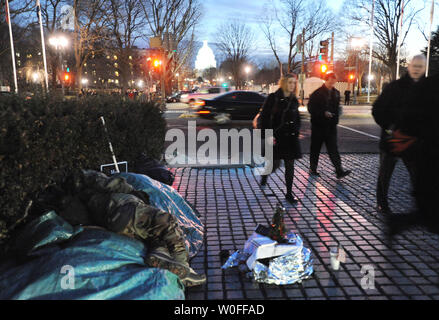 Pendler lassen Sie das Capitol Komplex wie ein obdachloser Mann schläft in der Nähe der Union Station am 27. Januar 2010. Eine viertel Meile entfernt, Präsident Barack Obama für die Wirtschaft und Arbeitsplätze konzentrieren wird, wenn er die Lage der Union zu einer gemeinsamen Sitzung des Kongresses liefert am Capitol Building (Dome im Hintergrund) am 27. Januar 2010 in Washington. UPI/Pat Benic Stockfoto