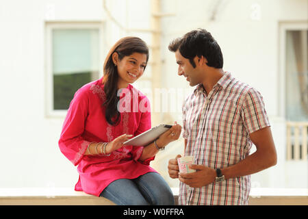 Frau mit einem digitalen Tablet und ihrem Mann daneben Sie Stockfoto