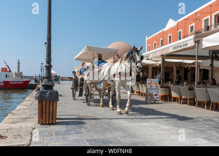 Chania, Kreta, Griechenland, Juni 2019. Einem oben offenen Pferdekutsche mit Fahrer und Beifahrer in der Altstadt von Chania, Kreta. Stockfoto