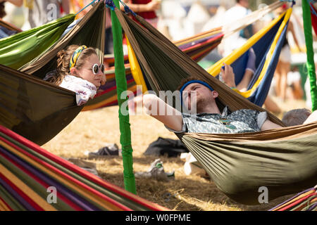 Festivalbesucher in der Sonne entspannen auf dem Glastonbury Festival in würdiger Farm, Pilton, Somerset. Stockfoto