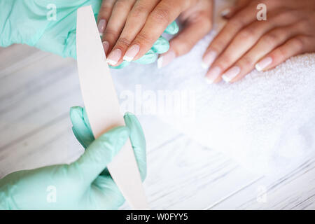 Maniküre. Geschickte Master der Maniküre holding Datei in Ihre Hände bei der Arbeit in ihrem Schönheitssalon Stockfoto