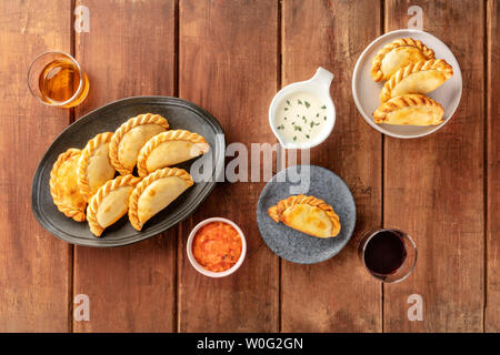 Empanadas mit Saucen und Wein, geschossen von oben auf einen dunklen Holzmöbeln im Landhausstil Hintergrund copyspace Stockfoto