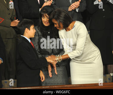 First Lady Michelle Obama grüßt Dallas Green, 11, Bruder von Christina Taylor Grün, 9, der in der Januar 8 Tötungen in Tucson Arizona getötet wurde, als sie eintrifft, um US-Präsident Barack Obama zu hören, seine Rede zur Lage der Union am 25. Januar 2011 in einer gemeinsamen Sitzung des Kongresses im Haus Kammer am Kapitol in Washington zu liefern. In der Mitte ist roxanna Grün. UPI/Pat Benic Stockfoto