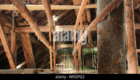 Alte hölzerne Scheune von innen, mit Sonneneinstrahlung nur aus einem kleinen Dach Fenster und einige Ritzen im Holz- wänden. Viel Heu und Stroh ist Ly Stockfoto