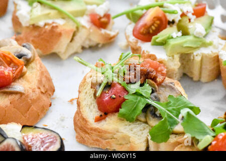 Sauber, gesund naschen Avocado, Tomate, Pilz und Feigen bereit, mit Kräuter, Blätter und ein kleines Stück Baguette serviert werden. Ideal bite Stockfoto