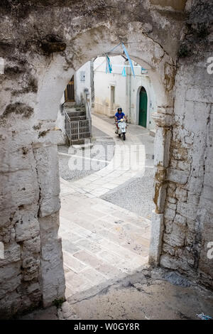 SPINAZZOLA, Italien - 21 AUGUST, 2018: Der Mensch, er reitet einen Vespa Roller auf einer gepflasterten Straße in der Altstadt von Spinazzola Stockfoto