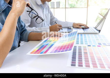 Team von Kollegen Grafiker zeichnen und retuschieren Bild auf dem Grafiktablett und wählen Sie Farbe swatch Proben für die Auswahl auf einem Laptop. Stockfoto