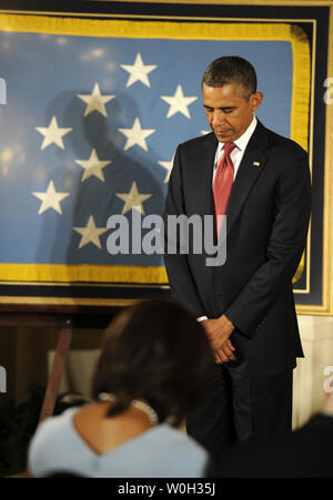 US-Präsident Barack Obama beugt seinen Kopf vor der Auftragsvergabe Ray Kapaun, Neffe von Vater Emil Kapaun, der Ehrenmedaille in seinem Namen posthum während einer Zeremonie im East Room des Weißen Hauses, 11. April 2013 in Washington, DC. Vater Kapaun, als US Army Kaplan, zu den amerikanischen Kriegsgefangenen während des Koreakrieges verabreicht und starb in Gefangenschaft. UPI/Mike Theiler Stockfoto