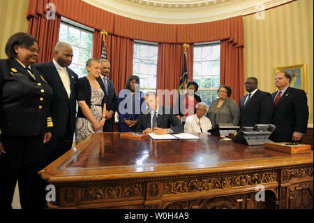 US-Präsident Barack Obama unterzeichnet eine Rechnung im Oval Office, 24. Mai 2013 in Washington, DC, die Benennung der Congressional Gold Medal zum Gedenken an das Leben der vier jungen Mädchen in der 16th Street Baptist Church Bombardierungen von 1963 in Birmingham, Alabama getötet. Zeugen (L-R) Surgeon General Regina Benjamin, Birmingham Bürgermeister William Bell, Dr Sharon Malone Halter, Justizminister Eric Holder, Rep Terri Sewell (D-AL), Thelma Pippen McNair (Mutter von Denise McNair), Lisa McNair (Schwester von Denise McNair), Dianne Braddock (Schwester von Carolel Robertson), Rev Arthur Preis, Jr (Pastor 16. Straße Bap Stockfoto