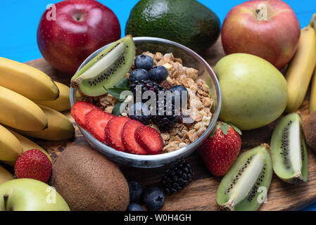 In der Nähe von hellen sortierte Früchte, Bananen, Äpfel, Mango, Kiwi, Erdbeeren, Blaubeeren, mit Getreide für ein gesundes Frühstück Stockfoto