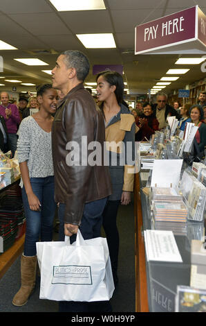 US-Präsident Barack Obama hält eine Tüte mit seinem Buch kauft, nachdem er und Töchter Malia (R) und Sasha Einkaufen am unabhängigen Buchhandlung Politik & Prosa, November 30, 2013, in Washington, DC. Das Shoppen fiel mit Small Business Samstag, eine Tradition, die Shopping für kleinere Kaufleute zu erhöhen. UPI/Mike Theiler Stockfoto