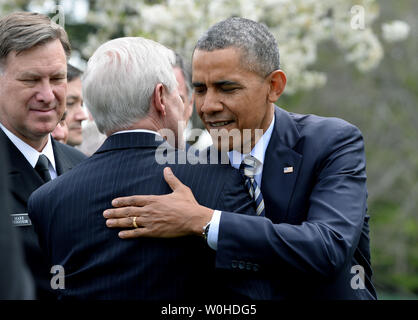 Präsident Barack Obama umarmt Sekretär der Marine Ray Mabus wie Obama grüßt die Zuschauer, nachdem er die Commander-In-Chief Trophäe an die Naval Academy Football Team im Rosengarten des Weißen Hauses in Washington, DC am 18. April 2014 vorgestellt. Obama sagte, dass die Spieler Engagement für ihr Land mehr Spezielle war ihr ihre Fußballmannschaft. UPI/Pat Benic Stockfoto